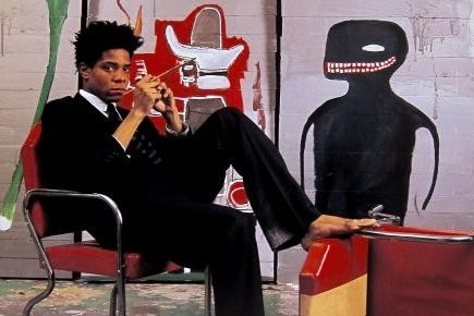 Jean-Michel Basquiat dans son atelier de New York en 1985, devant une de ses oeuvres
